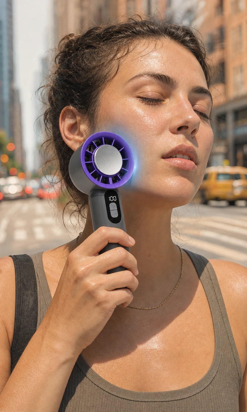 Woman using the BreezeTurbo cold-touch cooling plate on her cheek during a hot city day